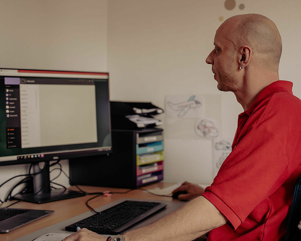 DRK Mitarbeiter sitzt vor dem Computer