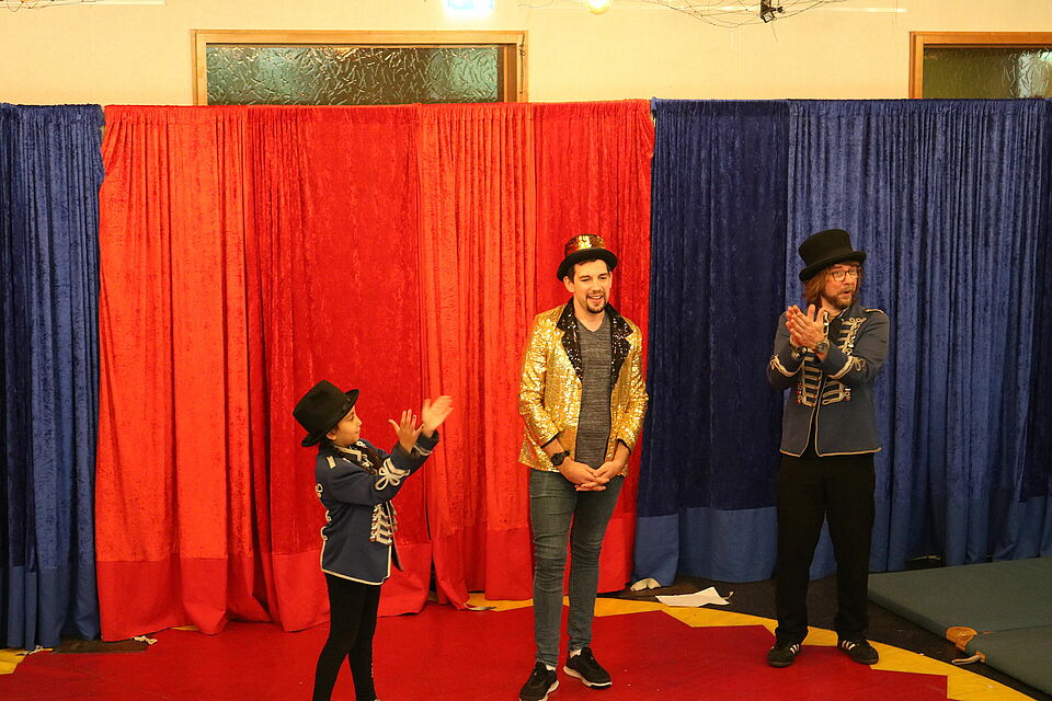 Kind und zwei Männer vor Zirkusvorhang