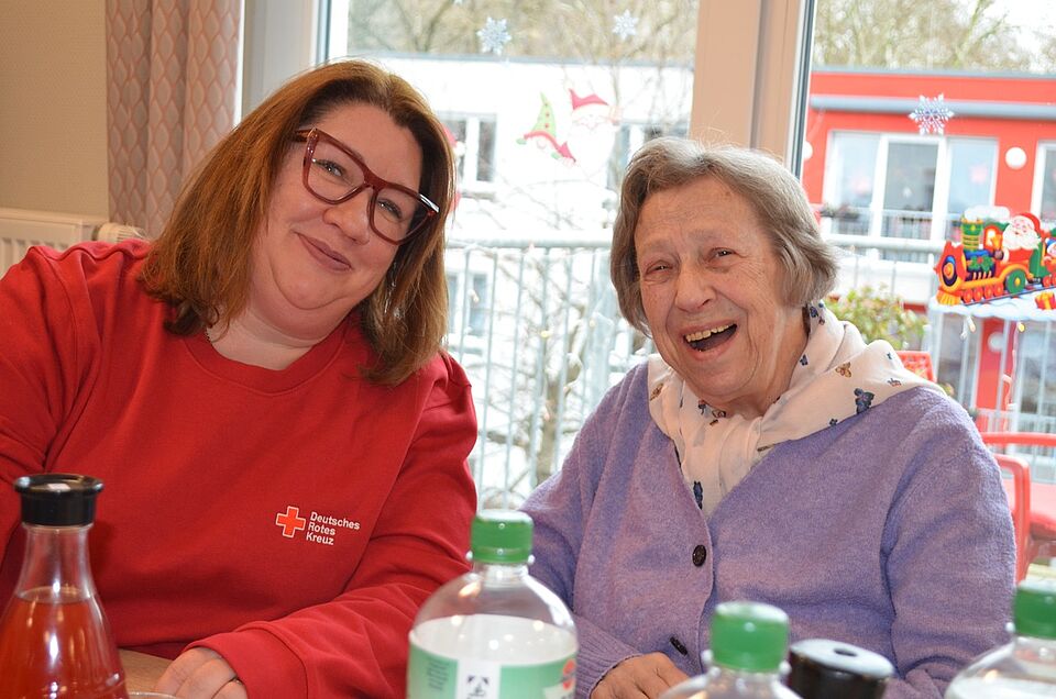 Pflegefachkraft sitzt mit Bewohnerin der Demenzwohngruppe am Tisch