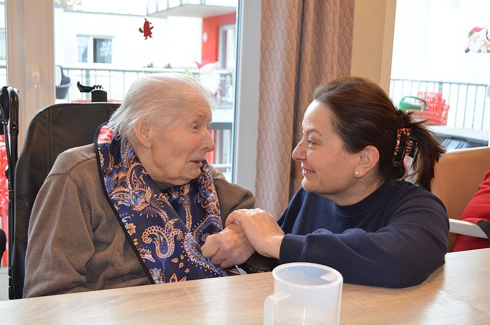 Bewohnerin im Rollstuhl, daneben Pflegerin