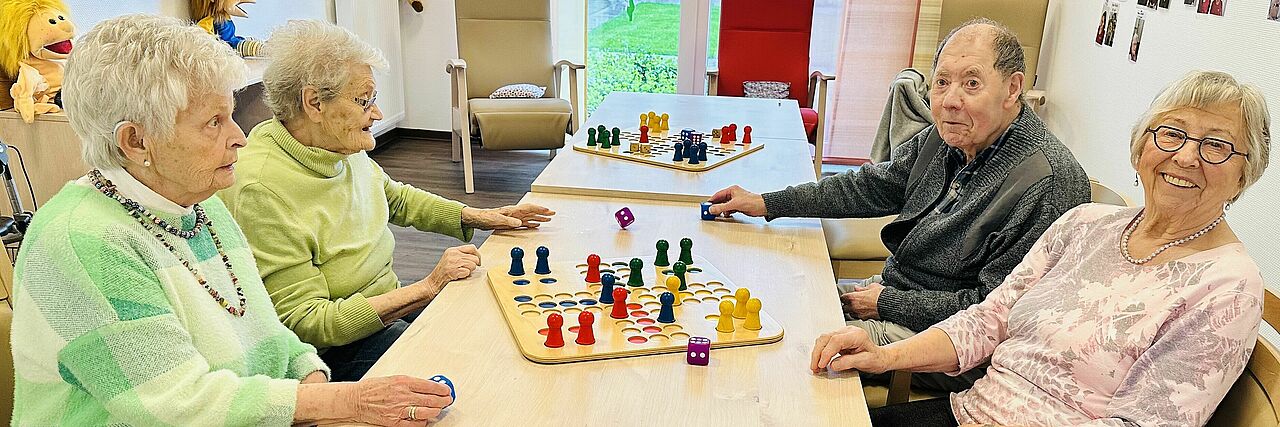 Senioren sitzen an einem Tisch und spielen Brettspiele
