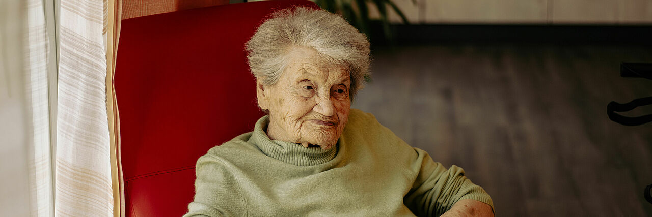 Ältere Dame sitzt im Sessel